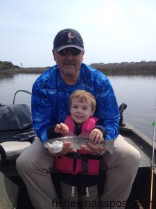 Luke Tierney (age 2) and his grandfather James Demyan with Luke's first fish, a speckled trout he caught and released after it bit a mud minnow in the backwaters near Oak Island. 