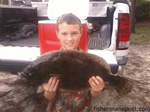 Michael Batts (age 8), of Southport, with his first flounder, a 3.7 lb. fish that he hooked near Bald Head Island while fishing with his grandfather.