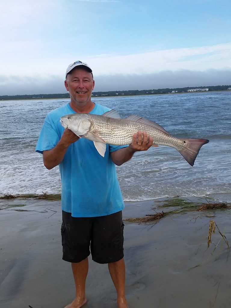 Jeffrey Coffey with a 34" red drum he caught and released after it bit a live mullet while he was fishing from the Sunset Beach shoreline.